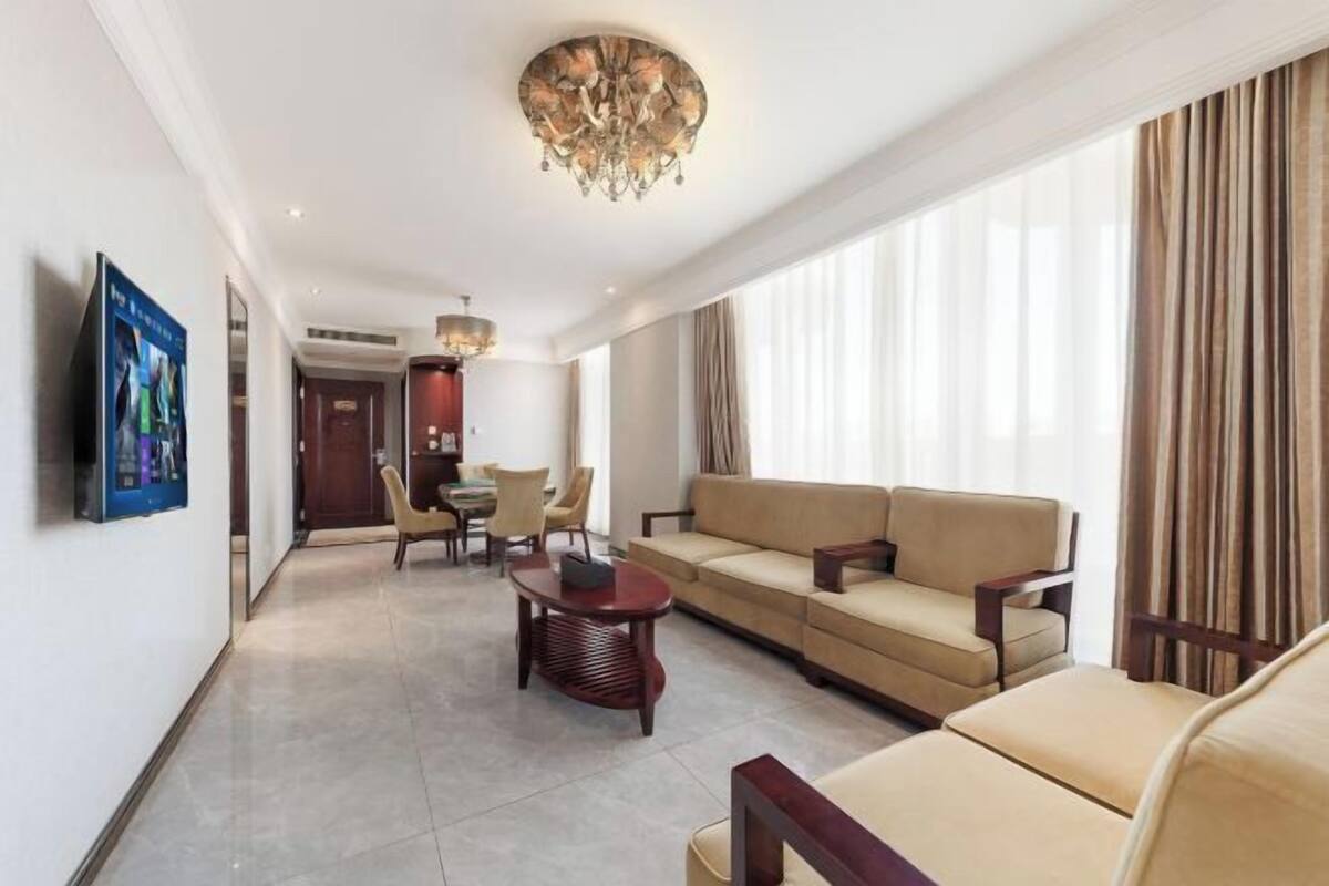 A modern living room with a sofa, a coffee table, and a TV mounted on the wall.