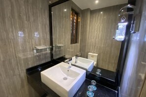 A modern bathroom with two sinks, a glass shower enclosure, and a large mirror.