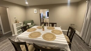 Une salle à manger avec une table rectangulaire dressée pour six personnes, entourée de six chaises.