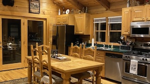 Una cocina estilo cabaña de madera con una mesa de comedor, sillas, un refrigerador, estufa y microondas.