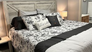 A bedroom with a bed, nightstands, a mirror, and wall art. - Beautiful Land's End Waterfront Condo (Osage Beach)