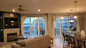 A living room with a sofa, a fireplace, a TV, and a dining area with chairs and a table. - Beautiful Land's End Waterfront Condo (Osage Beach)