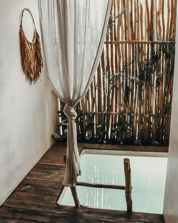 A room with a wooden floor, a bamboo fence, and a small pool. - Majaro Apartments (Tulum)