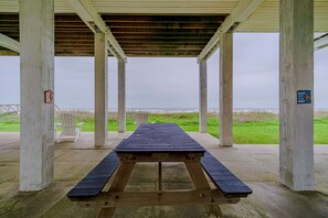 Ett picknickbord under ett tak med utsikt över stranden.