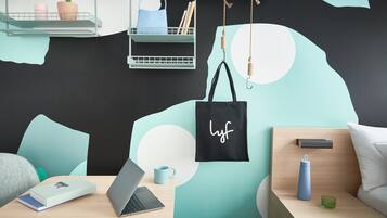 Una habitación moderna con una computadora portátil, libros, una taza y una bolsa de tela sobre una mesa de madera.