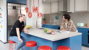 Una cocina moderna con una isla central, armarios azules y taburetes rojos.