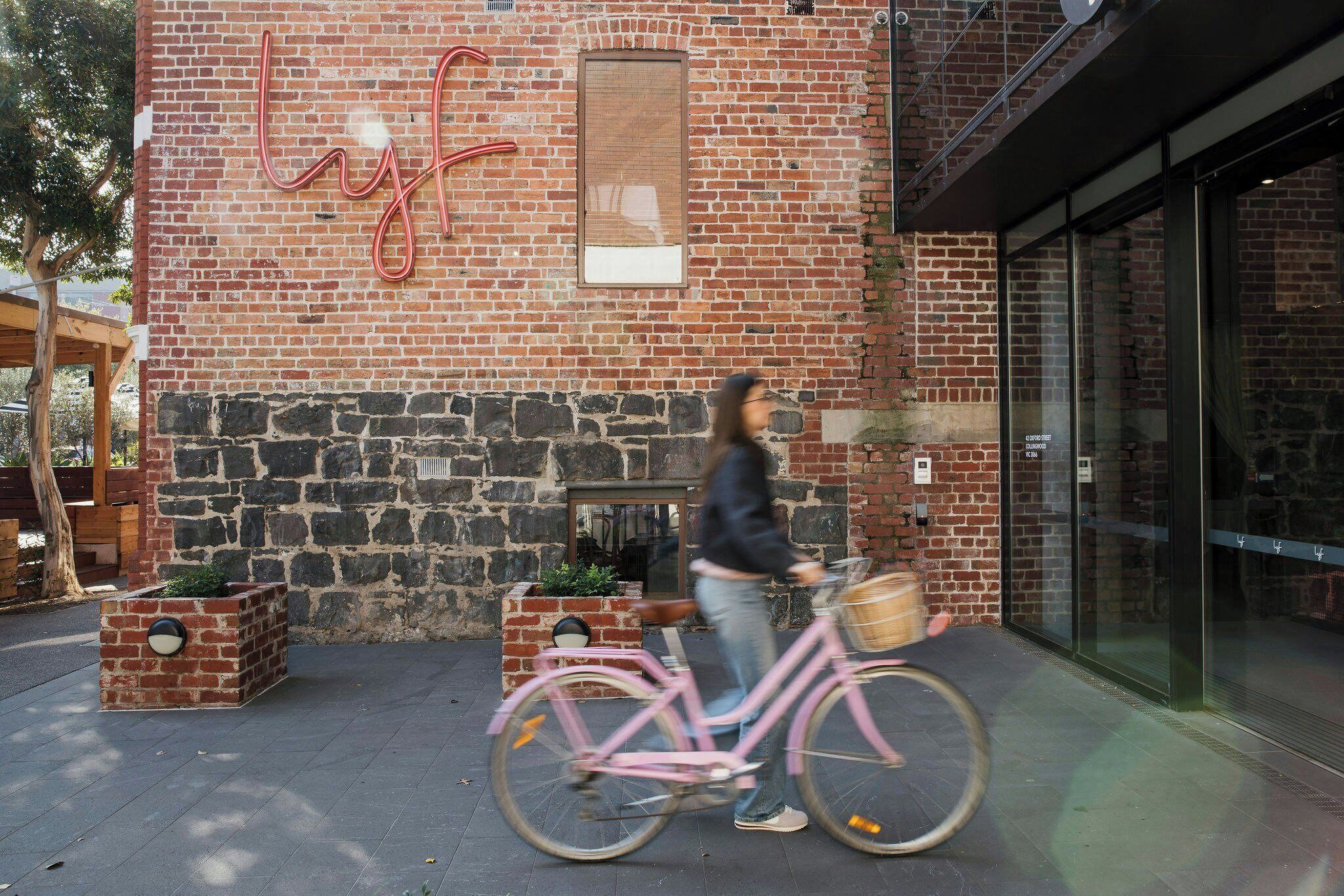 Un edificio de ladrillo con un gran letrero rojo, una pared de piedra y una entrada de vidrio.