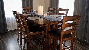 A dining area with a wooden table and chairs, a candle, and a placemat.