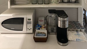 A kitchen with a microwave, toaster, coffee maker, and various kitchenware.