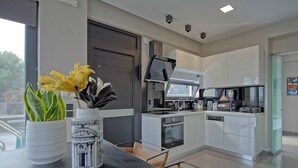 A modern kitchen with a large window, a dining area with a table and chairs, and a small side table with decorative items.