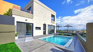 A modern house with a swimming pool, a balcony, and a view of the city.