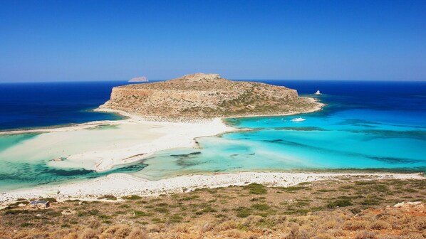 Un paisaje costero con una isla rocosa destacada y una playa de arena.