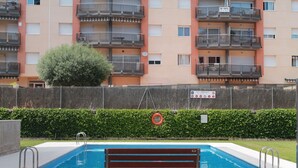 En swimmingpool med en bänk, omgiven av ett staket och en häck.