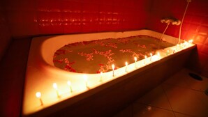 Eine Wanne mit Rosenblättern und Kerzen.
