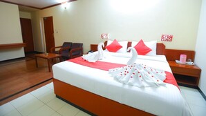 Ein Hotelzimmer mit einem großen Bett, zwei Sessel, einem kleinen Tisch und einem Nachttisch.