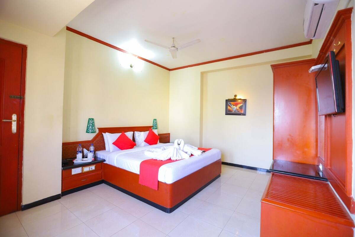 A hotel room with a bed, bedside tables, a TV, and a ceiling fan.