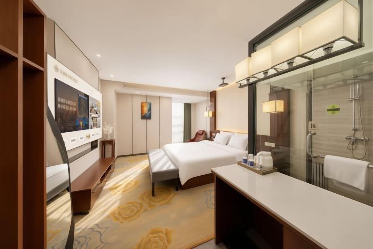 Ein Hotelzimmer mit Bett, Fernseher, Badezimmer inklusive Spiegel und Schreibtisch.