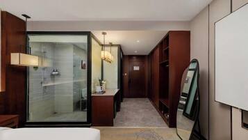 A modern hotel bathroom with a glass shower enclosure, a vanity with a mirror, and a large mirror on the wall.
