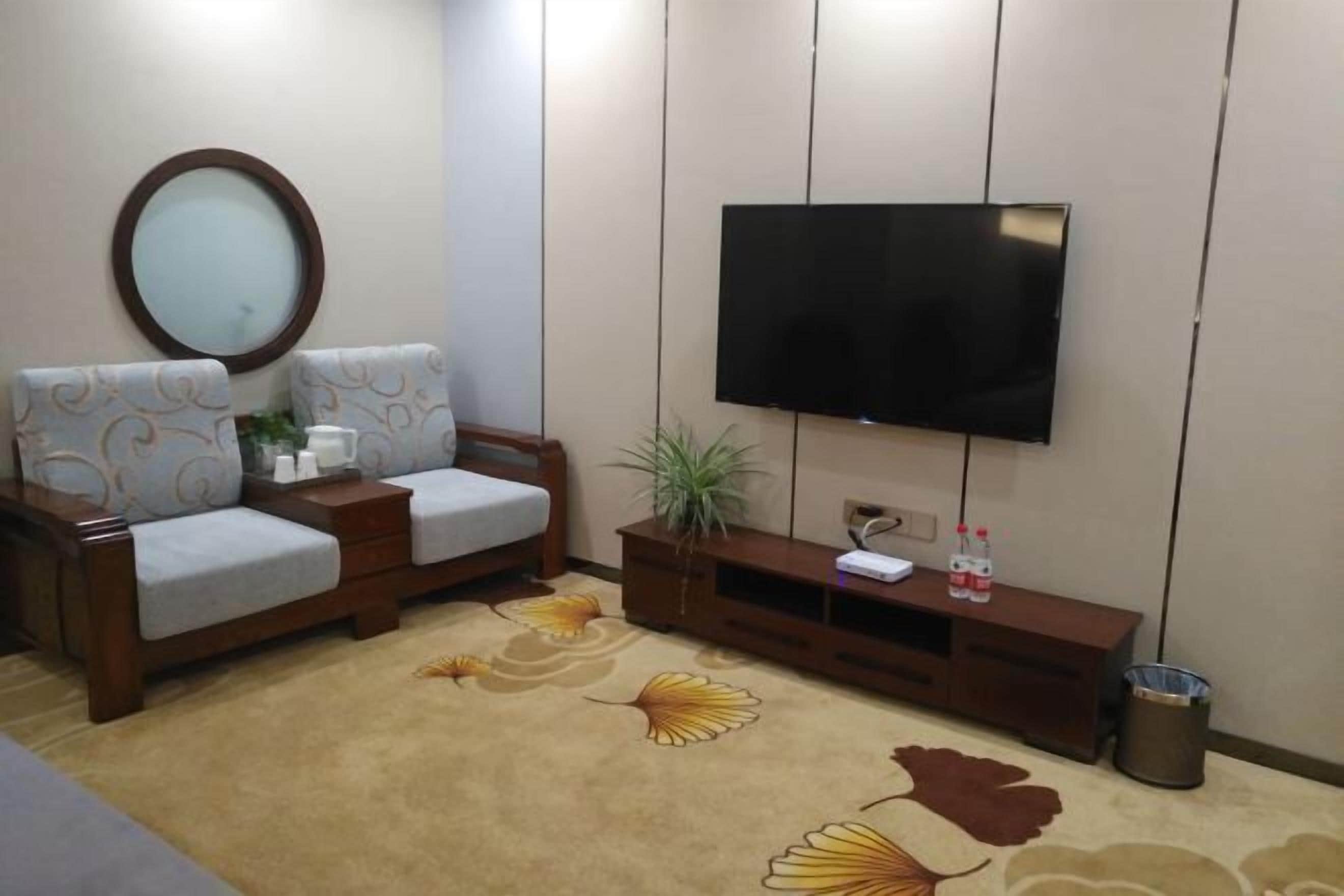 Un salon comprenant un canapé, un téléviseur, une petite table et un tapis décoratif.