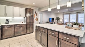 A modern kitchen with dark cabinets, a large island, and pendant lighting. - Mid-Century Modern Escape in Central Lakeland! (Lakeland)