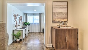 A hallway with a wooden floor, a desk with a potted plant, a cabinet with kitchen items, and a world map on the wall. - Mid-Century Modern Escape in Central Lakeland! (Lakeland)