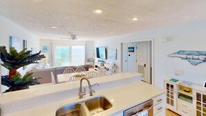 Una cucina moderna con isola centrale, mobili bianchi e zona pranzo con sedie.