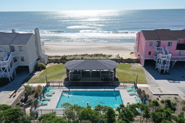 A beachfront hotel with a swimming pool, beach view, and two buildings with balconies.