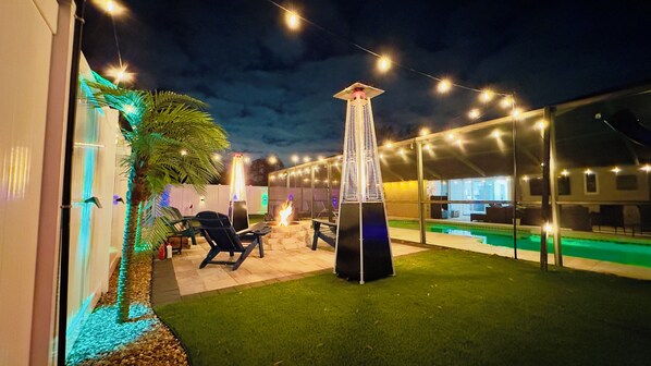 A pool area with a tall, narrow structure, possibly a water feature, surrounded by string lights.