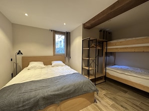 Una camera da letto con un letto a castello, una testiera in legno, un comodino con una lampada e una finestra vista verdega.