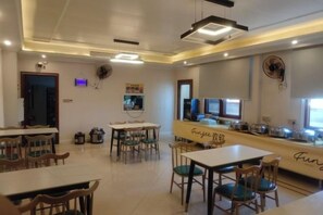 A restaurant with multiple tables and chairs, a counter with a menu, and a television screen. - MAISON Hotel (Liuyang Economic Development Zone, Coach Station, Liuyang) (Liuyang)