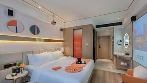 A modern hotel room with a neatly made bed, a small bedside table with a lamp, a mirror, and a view of the city through the window. - MAISON Hotel (Liuyang Economic Development Zone, Coach Station, Liuyang) (Liuyang)