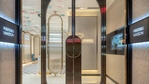 A modern hotel entrance with a glass door, a sign reading "MAISON," and a digital display on the wall. - MAISON Hotel (Liuyang Economic Development Zone, Coach Station, Liuyang) (Liuyang)