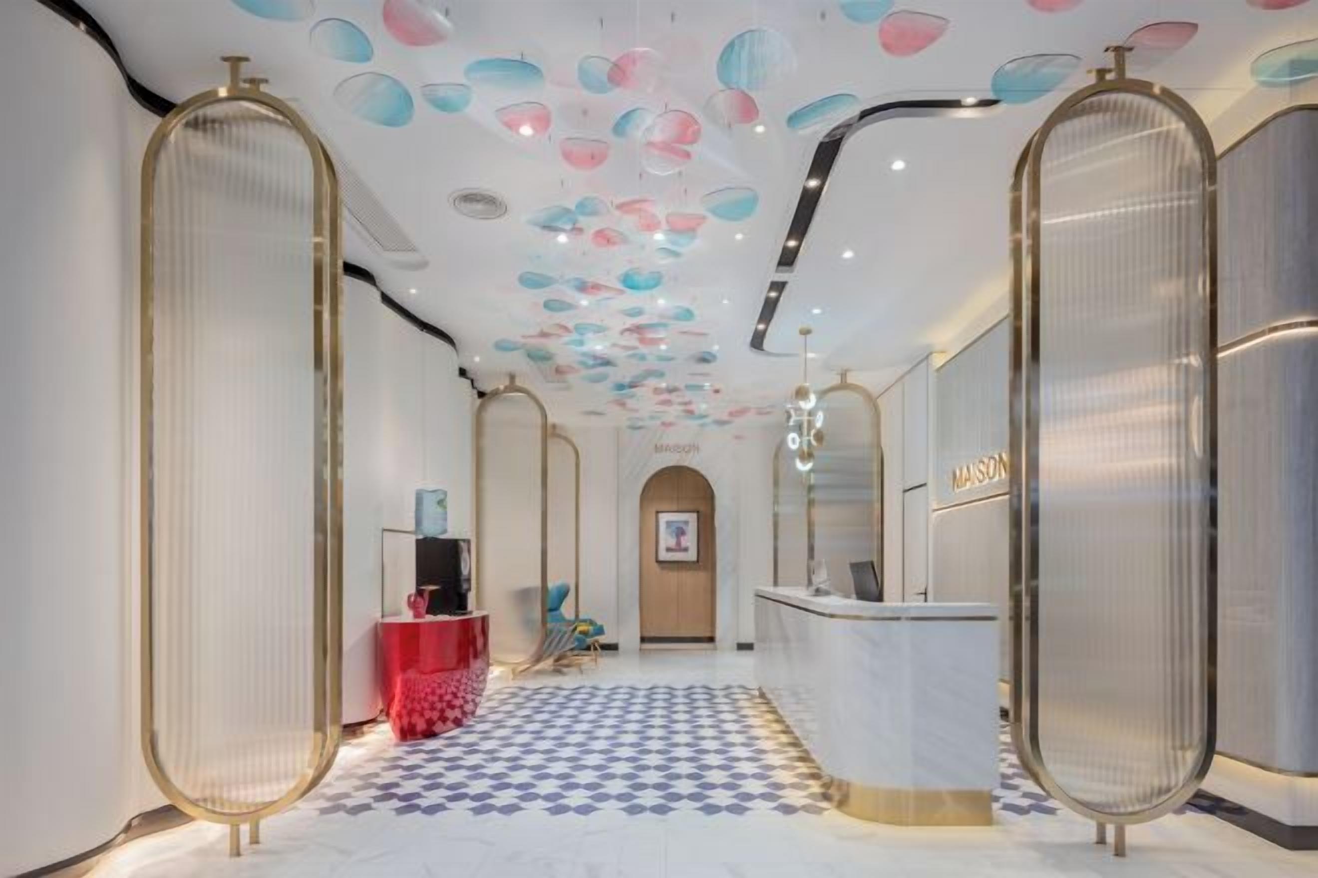 A hotel lobby with a check-in counter, a reception desk, and a patterned floor.