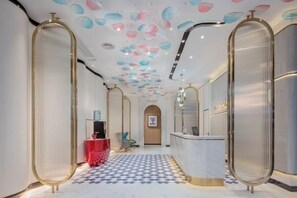 A hotel lobby with a check-in counter, a reception desk, and a patterned floor. - MAISON Hotel (Liuyang Economic Development Zone, Coach Station, Liuyang) (Liuyang)