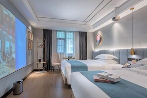 A modern hotel room with two beds, a desk, a chair, and a large screen displaying a presentation.