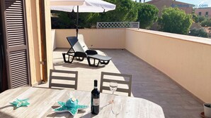 A balcony with a table, chairs, a bottle of wine, and a star-shaped decoration.