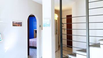 Un corridoio con una porta blu, una scala con ringhiere in metallo e un piccolo quadro appeso al muro.