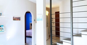 Ein Flur mit einer blauen Tür, einer Treppe mit Metallgeländern und einem kleinen Bild in einem Rahmen an der Wand.