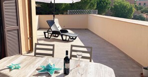 A balcony with a table, chairs, a bottle of wine, and a star-shaped decoration.