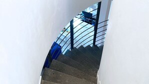 A staircase with a glass railing and a white wall.
