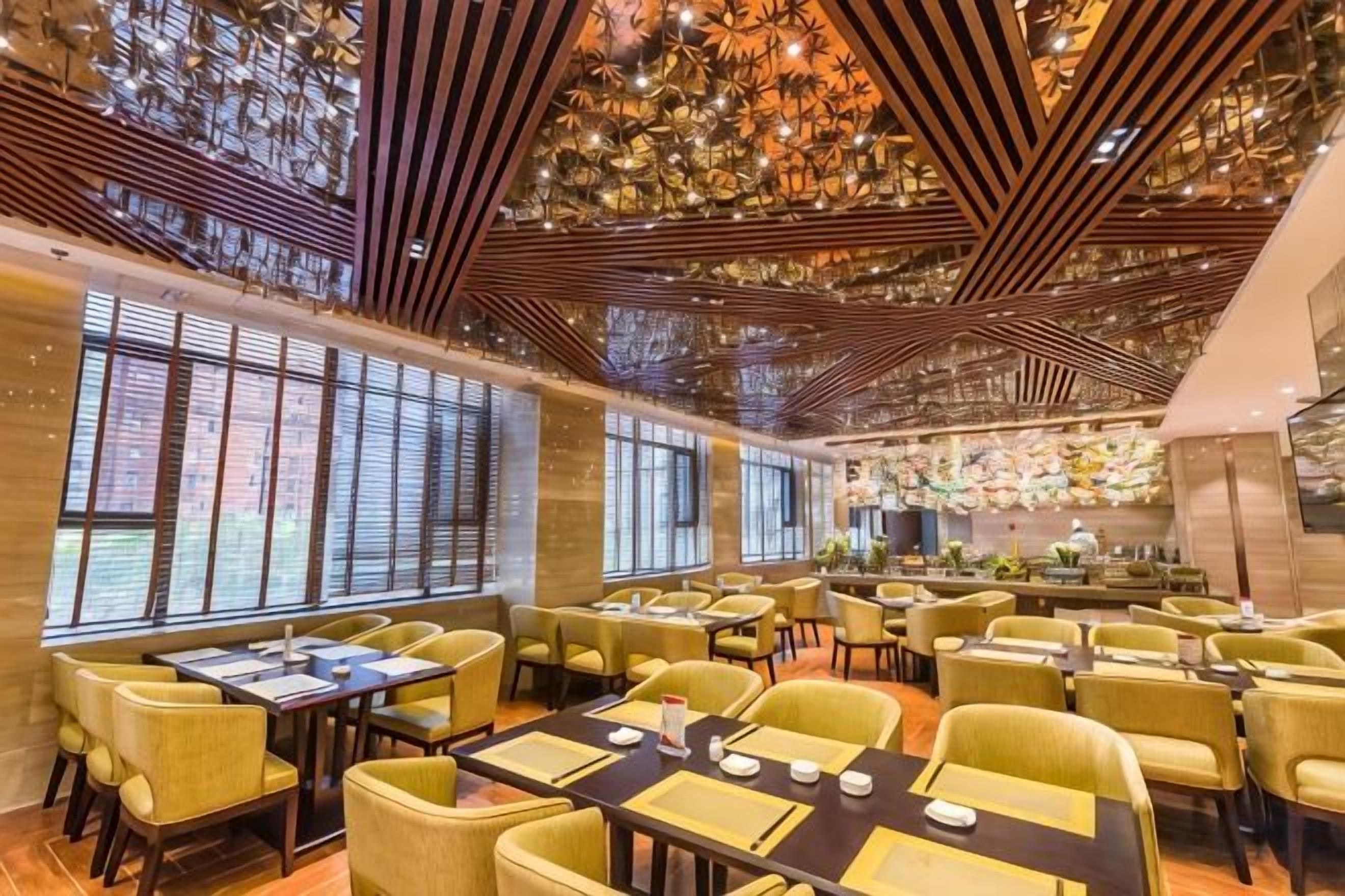 Un restaurante con varias mesas y sillas, amplias ventanas y un techo decorativo.