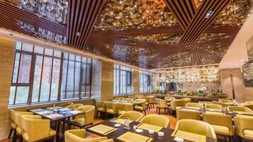 Un restaurante con varias mesas y sillas, amplias ventanas y un techo decorativo.