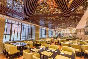 Un restaurant doté de nombreuses tables et chaises, de grandes fenêtres et d’un plafond décoratif.