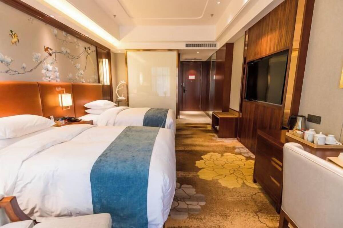 A hotel room with two beds, a TV, a desk, and a bathroom door.