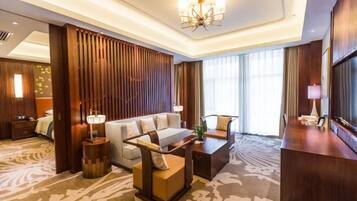 A modern hotel room with a sofa, a coffee table, a TV, and a patterned carpet.
