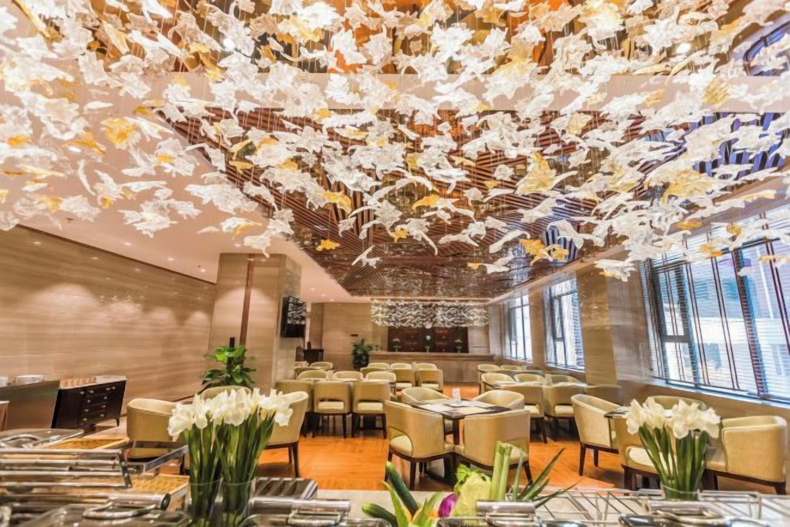 Ein Hotel-Essbereich mit Tischen, Stühlen und floralen Tischdekorationen.