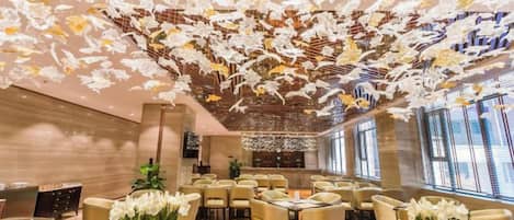 A hotel dining area with tables, chairs, and floral centerpieces.