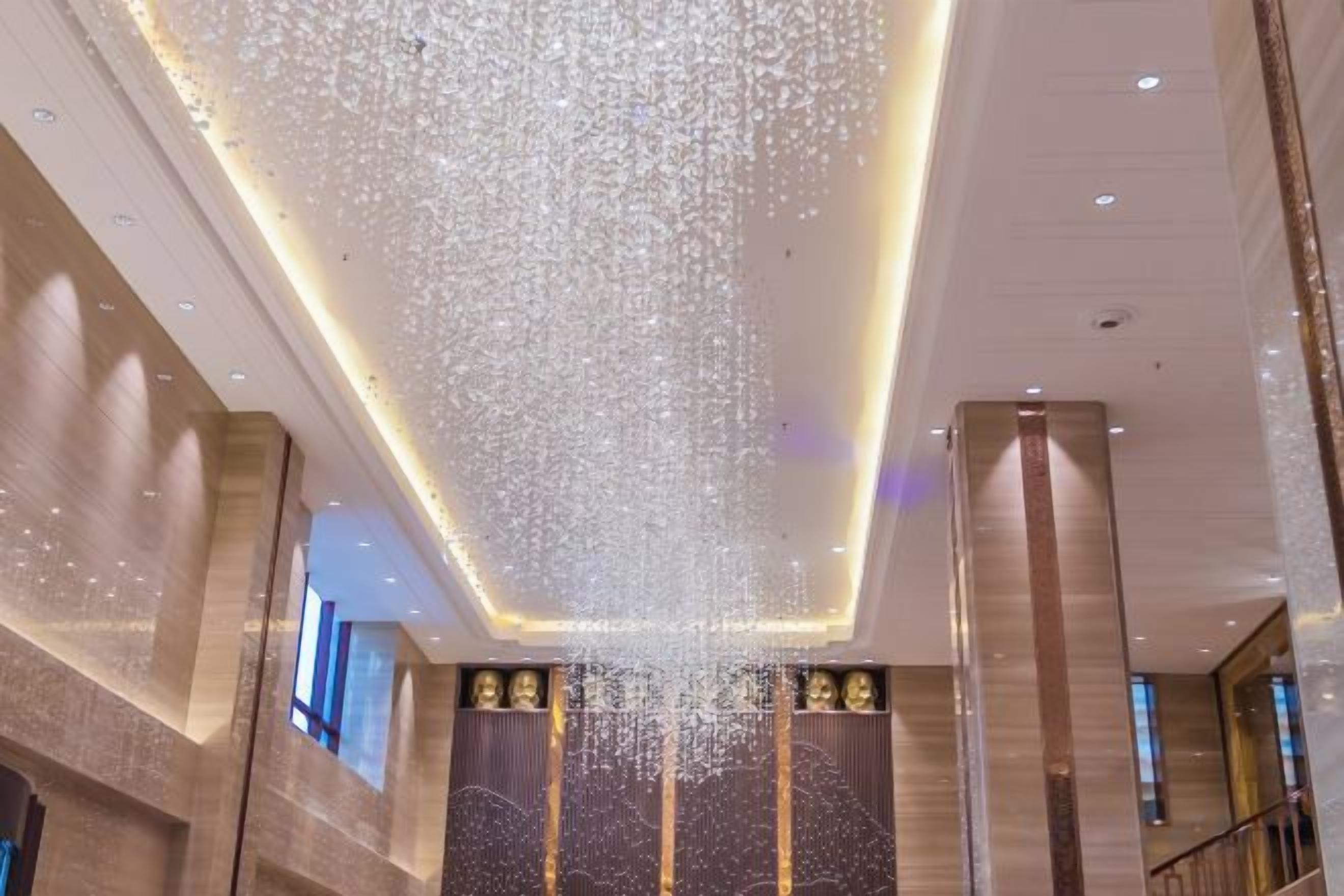 A lobby with a high ceiling, a large chandelier, and a staircase.