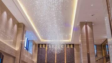 A lobby with a high ceiling, a large chandelier, and a staircase.