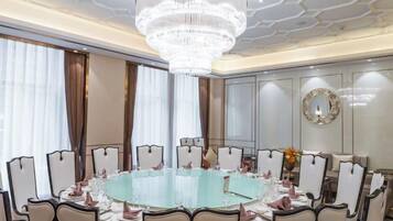 A formal dining room with a round table, chairs, and a chandelier.